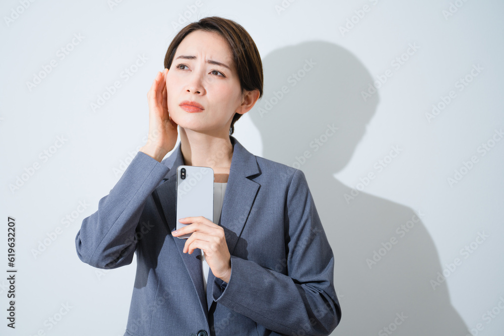 スマートフォンを持ちながら悩んでいる若い女性　ビジネスイメージ