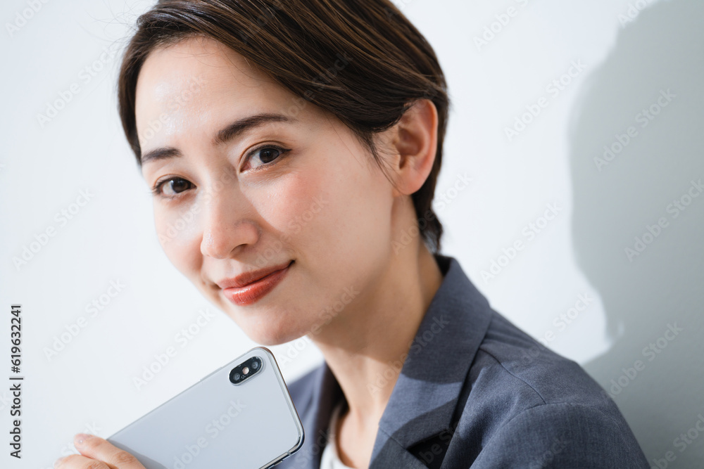 スマートフォンを持って考える若い女性 ビジネスイメージ スマートフォンを持って考える若い女性 ビジネスイメージ
