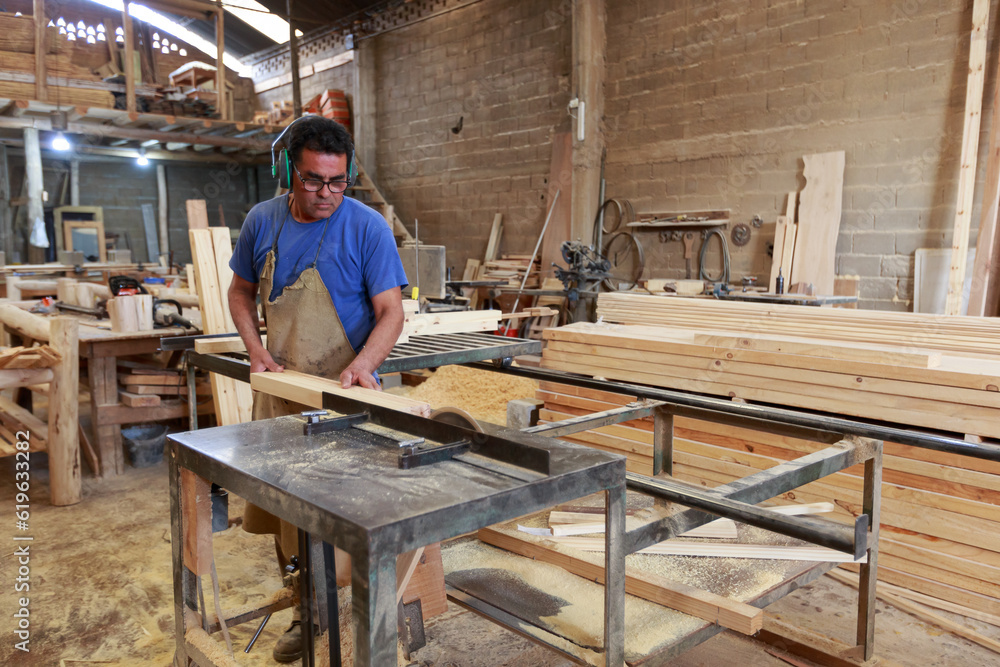 Craftsman at Work: Woodworker Using a Table Saw to Cut a Board in a Woodworking Studio Craftsman at Work: Woodworker Using a Table Saw to Cut a Board in a Woodworking Studio