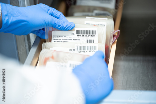 Close up scientist hand holding red blood bag in storage refrigerator at blood bank unit laboratory.Blood bags received from blood donations will be used in patients.Save life medical concept. photo