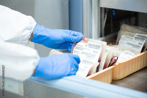 Close up scientist hand holding red blood bag in storage refrigerator at blood bank unit laboratory.Blood bags received from blood donations will be used in patient.Save life medical concept.