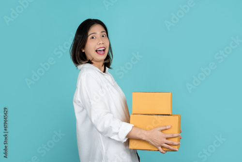 Young Cheerful beautiful asian woman with many parcel cardboard standing on isolated turquoise background.