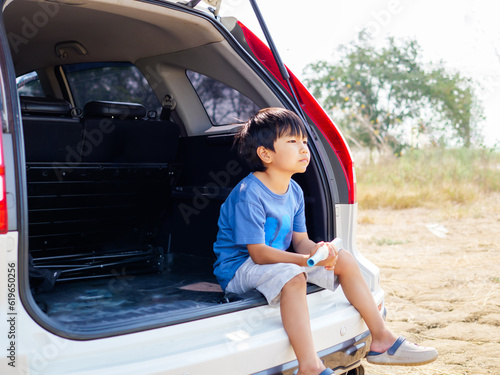 Asian child boy sitting and thinking with upset unhappy face in rear of white car. Concept of dream, future, relationship.