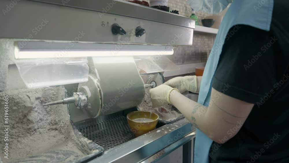 Dental technician busy with the denture substitution production process. Dental technician producing denture replacement using modern equipment. Dental technician deals with the denture production. Dental technician busy with the denture substitution production process. Dental technician producing denture replacement using modern equipment. Dental technician deals with the denture production.