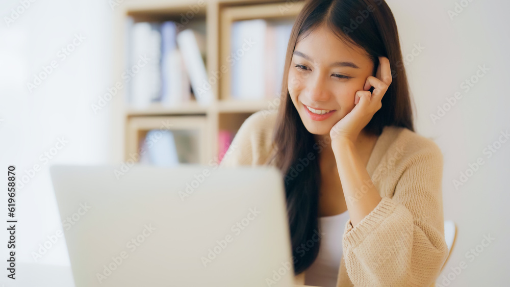 Young asian woman working at home. Happy female using computer laptop on desk at house Young asian woman working at home. Happy female using computer laptop on desk at house