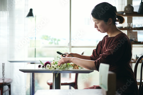 開店前のカフェで花をいける日本人女性