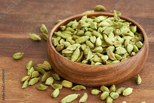 pile of green cardamom cardamon in wood plate on table background. green cardamom cardamon. heap of green cardamom cardamon food background