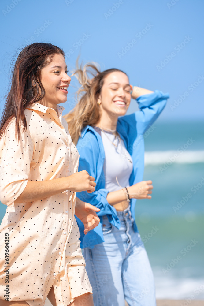 Two friends having fun running on the beach shore Two friends having fun running on the beach shore