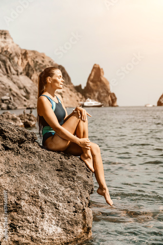 Woman travel summer sea. A happy tourist in a blue bikini enjoying the scenic view of the sea and volcanic mountains while taking pictures to capture the memories of her travel adventure.