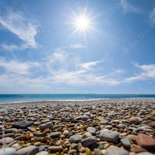 sea coast with pebbles under a sparkle sun, summer sea vacation scene