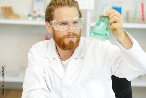 man looking at liquid in flask