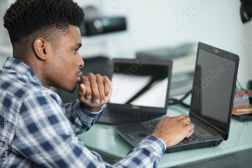 young technician in a workshop with several laptops