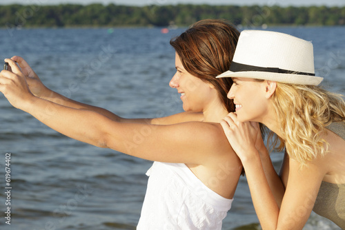 sisters taking selfie with smart phone in the lake