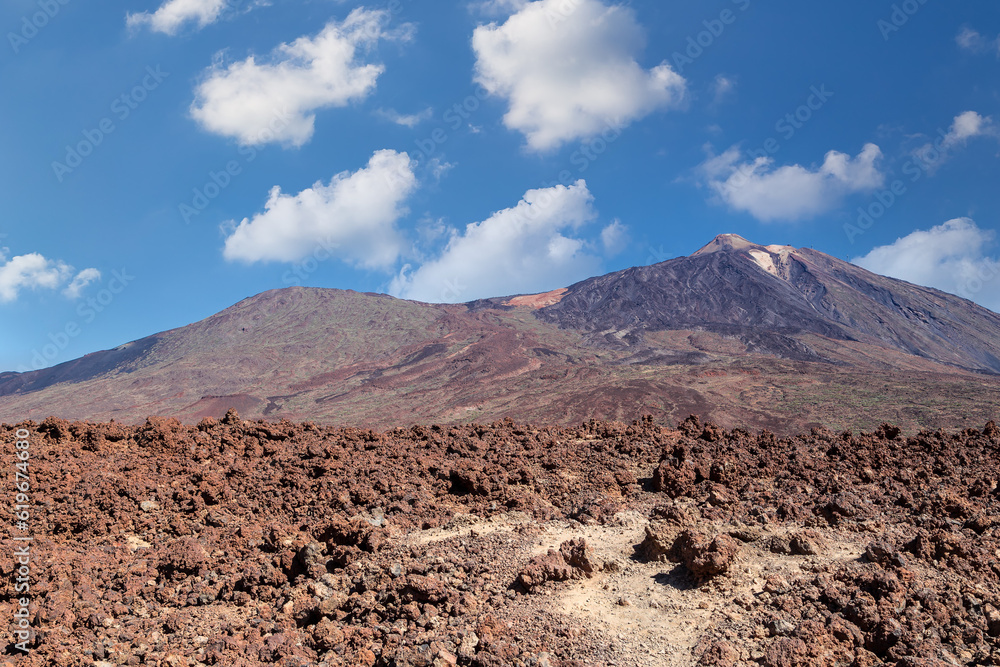 The famous El Teide volcano in Tenerife, Canary islands, Spain. Volcanic landscape in front a blue sky and white clouds.