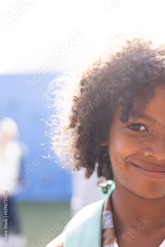 Vertical half face portrait of smiling african american elementary schoolboy outdoors, copy space photo