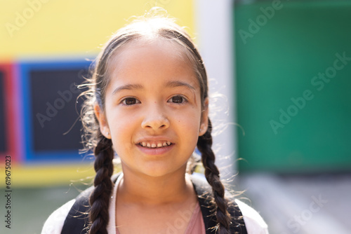 Portrait of smiling cauasian elementary schoolgirl in school playground, copy space photo