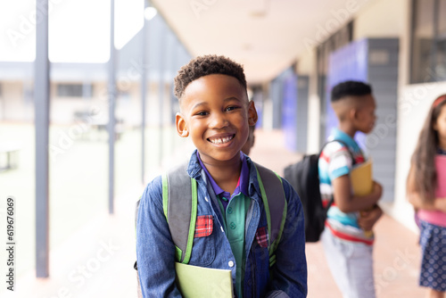 Portrait of smiling african american schoolboy in elementary school corridor, with copy space