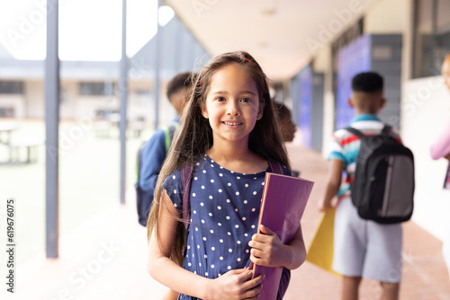 Portrait of smiling cacuasian schoolgirl in elementary school corridor, with copy space photo