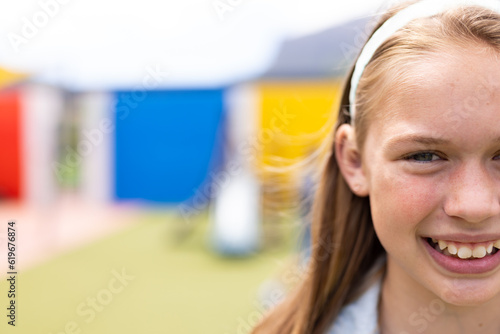 Half face portrait of smiling caucasian schoolgirl in schoolyard, with copy space photo