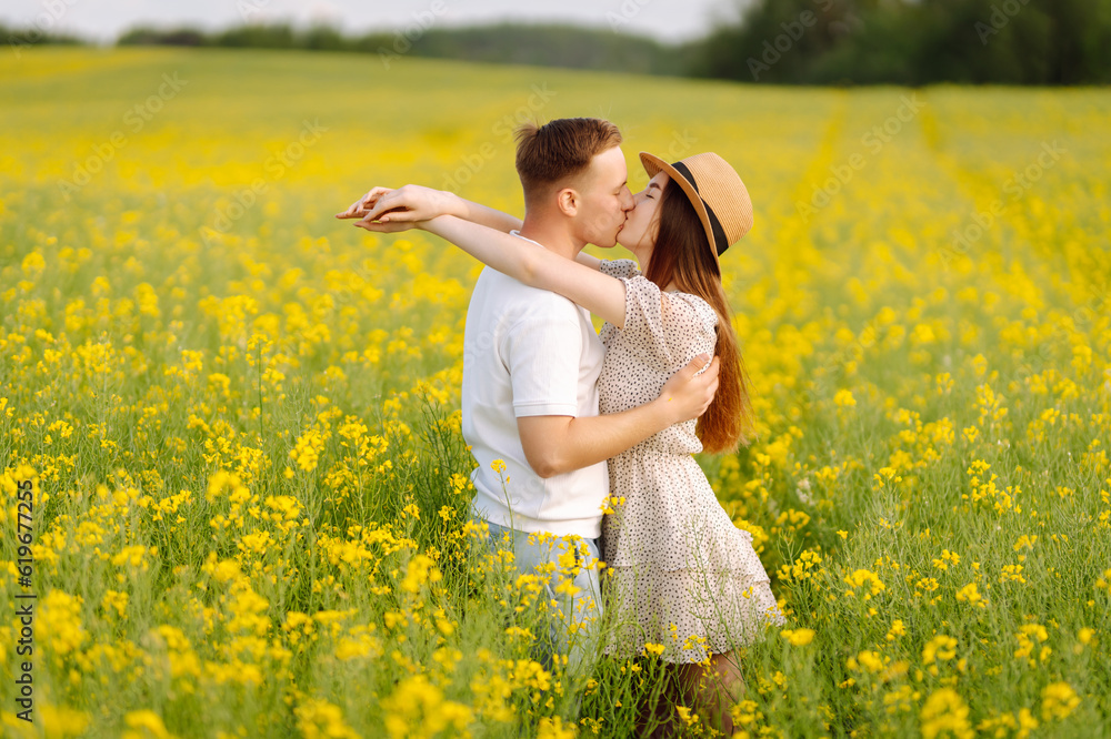 Young couple in love walks through a rapeseed field. Happy men and women in style enjoy the time spent together. The concept of love, test, relationship. Young couple in love walks through a rapeseed field. Happy men and women in style enjoy the time spent together. The concept of love, test, relationship.