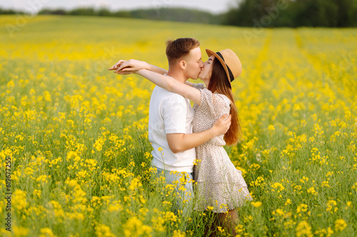 Young couple in love walks through a rapeseed field. Happy men and women in style enjoy the time spent together. The concept of love, test, relationship. © maxbelchenko