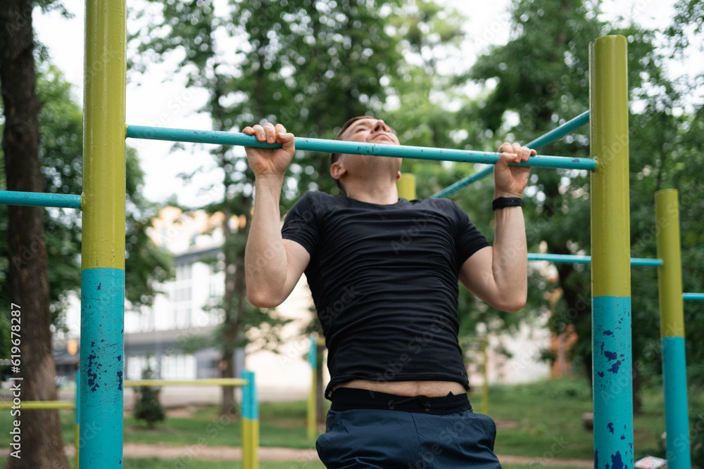 Middle age man doing pull-ups on the outdoors workout area