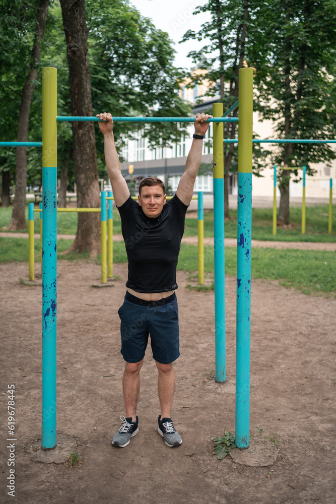 Fototapeta premium Middle age man doing pull-ups on the outdoors workout area