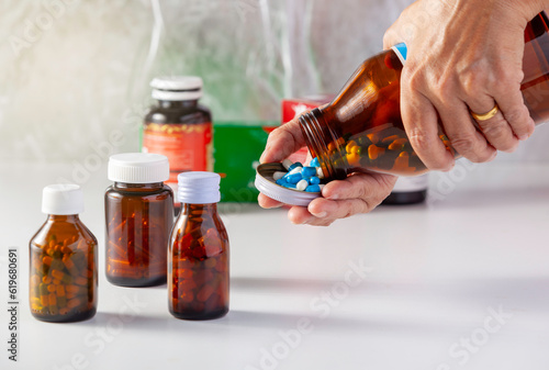 Elderly woman pouring pills out of pill bottles and has a medicine bottle placed on a white background several bottles