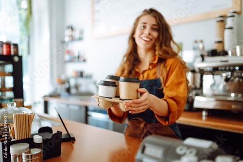 Best coffee for you. Cheerful woman in an apron at the bar counter holds coffee glasses in a cafe. Takeaway food concept.