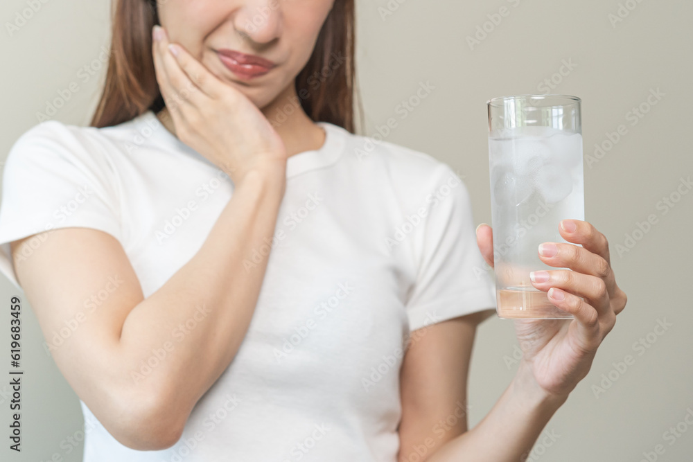 Suffering from toothache, blur asian young woman touch cheek, face expression ache or feel pain, sensitive molar teeth, hand holding glass of water with ice, inflammation when drink cold, healthcare. Suffering from toothache, blur asian young woman touch cheek, face expression ache or feel pain, sensitive molar teeth, hand holding glass of water with ice, inflammation when drink cold, healthcare.