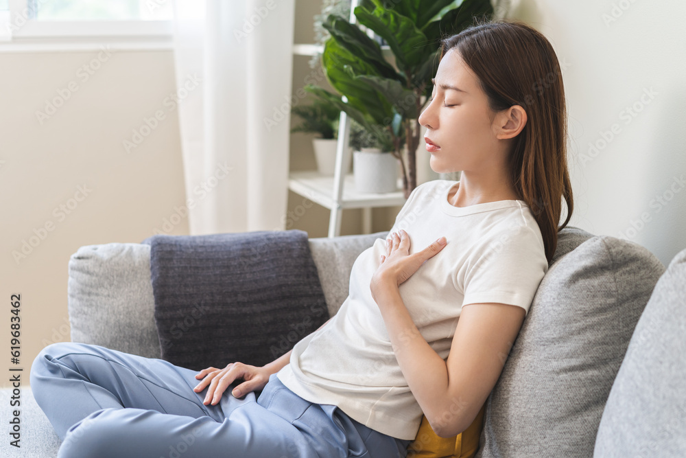Acid reflux disease, suffer asian young woman have symptom gastroesophageal, esophageal, stomach ache and heartburn pain hand on chest from digestion problem after eat food, Healthcare medical concept Acid reflux disease, suffer asian young woman have symptom gastroesophageal, esophageal, stomach ache and heartburn pain hand on chest from digestion problem after eat food, Healthcare medical concept