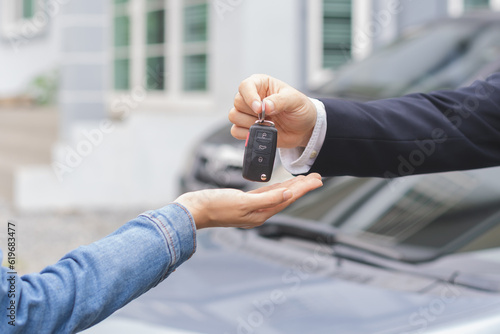 Foto Business car rental, sell or buy service, dealership hand of agent dealer, sale man giving auto key of vehicle to customer renter, buyer young woman receiving, client or tenant, transfer automobile