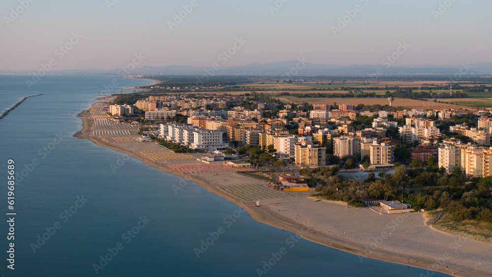 aerial shot of sandy beach with umbrellas and town background