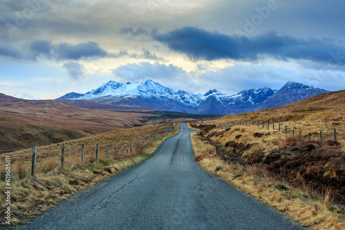 A winding road leads towards the magnificent snowcapped Cuillin mountains on the picturesque Isle of Skye, Scotland. photo