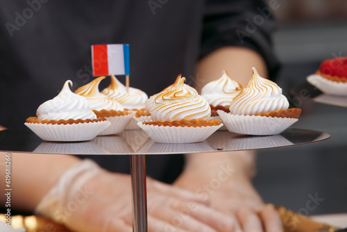 Sale of desserts and sweets at the French wine and food festival in holesovice, Prague. Closeup of metal tray with mini tarts with flambé meringue and French tricolor. photo