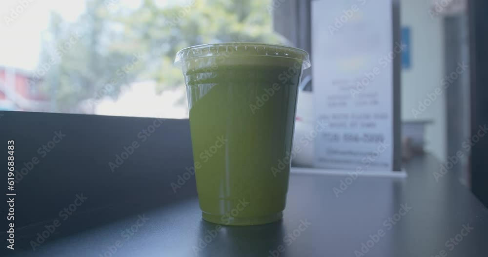 Close Up Dolly Forward of a Green Juice in a Cup by a Window Close Up Dolly Forward of a Green Juice in a Cup by a Window