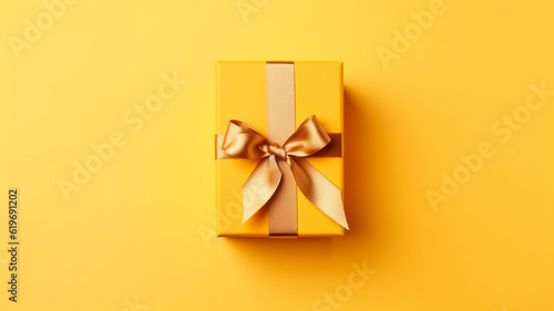 Golden ribbon gift box on yellow background, copy space, birthday/Christmas present, flat lay, top view concept. Generative AI