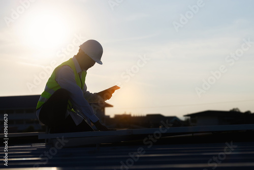 Service Engineer use tablet working inspection installation solar cell on the roof. Technician maintenance solar cells on roof factory under morning sunlight. Technology solar energy renewable.