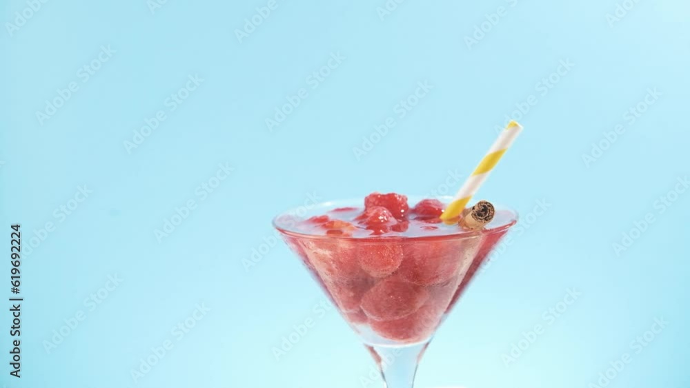 Raspberry cocktail Summer drink on cyan with yellow striped straw Raspberry cocktail Summer drink on cyan with yellow striped straw