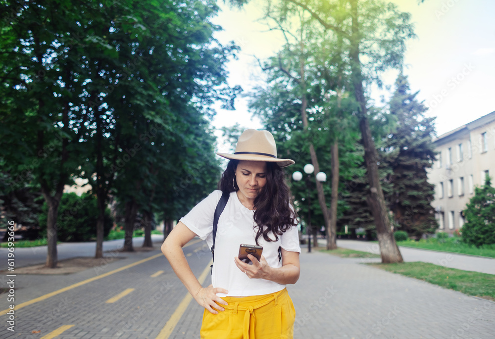 Traveler girl is looking for a way in an unfamiliar city using phone and maps. Tourism, visiting new places, communication with passers-by. Modern technologies, digitalization, mobile phone navigation