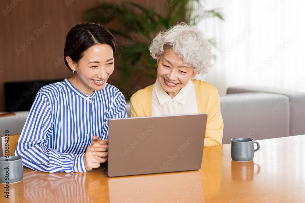 リビングでノートパソコンの画面を見ている日本人女性2人 リビングでノートパソコンの画面を見ている日本人女性2人