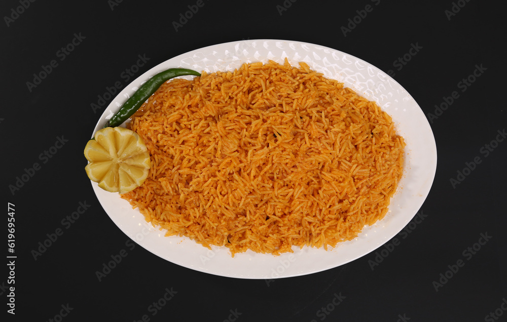 Cooked Arabian Yellow Rice black background garnished with lemon and chilly Cooked Arabian Yellow Rice black background garnished with lemon and chilly