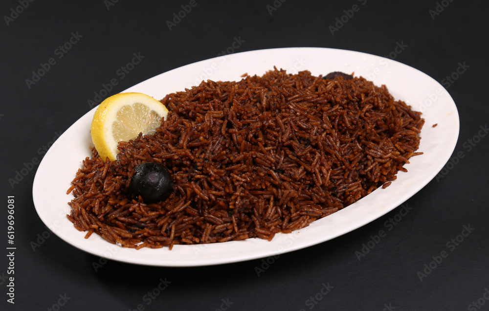 Rice mixed with fish masala brown color black background garnished with dried and fresh lemon black background Rice mixed with fish masala brown color black background garnished with dried and fresh lemon black background