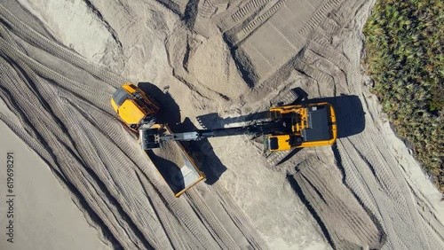 4k aerial overhead shot of excavators digging in the sand and working on the beach.