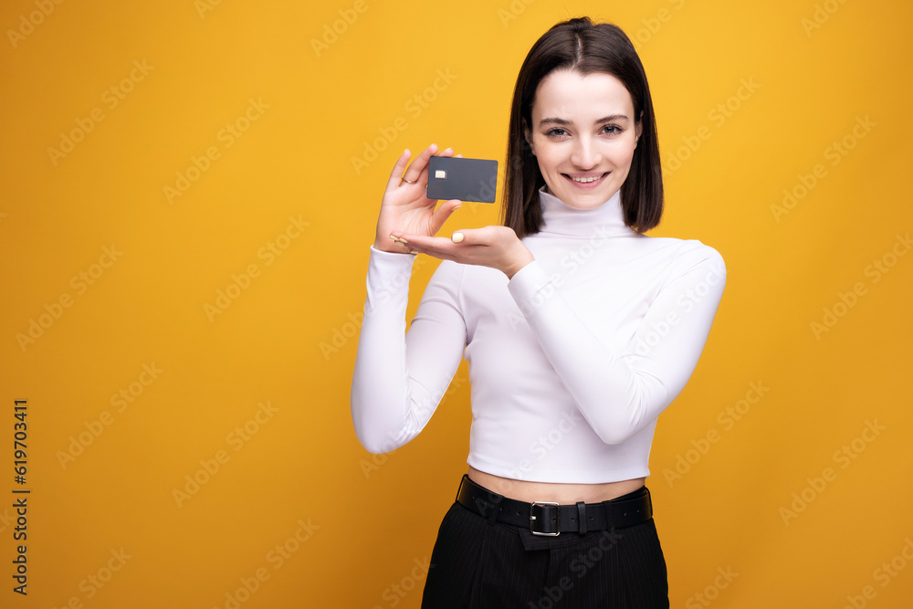 Close up portrait of young smiling business woman holding credit card, isolated on yellow background. Close up portrait of young smiling business woman holding credit card, isolated on yellow background.