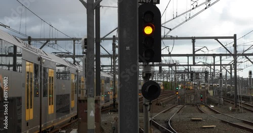 Camera focuses on yellow train signal as trains pass around. Urban metro transport show