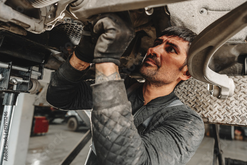 Auto mechanic repairs running gear of a car in car service