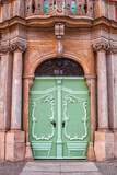 Antique wooden light green doors on city street, front view. Vintage painted double door, victorian style