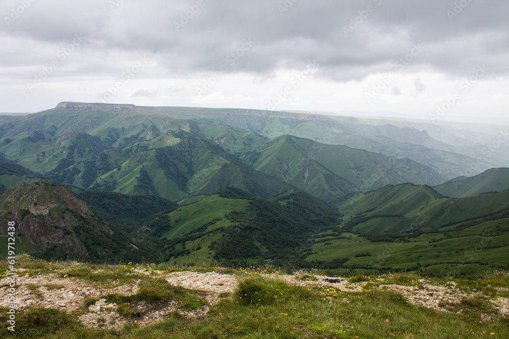 Dramatic landscape - panoramic top view of the canyon with green hills in the morning misty haze and cloudy sky with space to copy on the Bermamyt plateau in Karachay-cenrkessiya Dramatic landscape - panoramic top view of the canyon with green hills in the morning misty haze and cloudy sky with space to copy on the Bermamyt plateau in Karachay-cenrkessiya