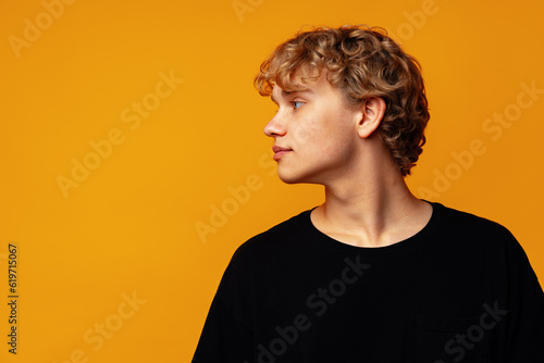 Obraz na plátně Young curly man looking to the side against yellow background